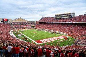 Picture of Camp Randall and Barry Alverez Field. The stadium is full of fans, mostly in red. The fans are watching a football game.