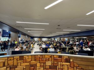 A wide shot of students gathered for the award assembly sitting in chairs and at tables. They are in a common area.