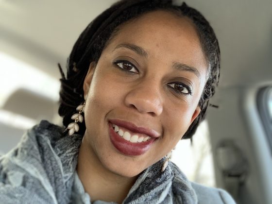 Pictured is Cassaundra Thorpe. Cassaundra is smiling and wearing a gray scarf.