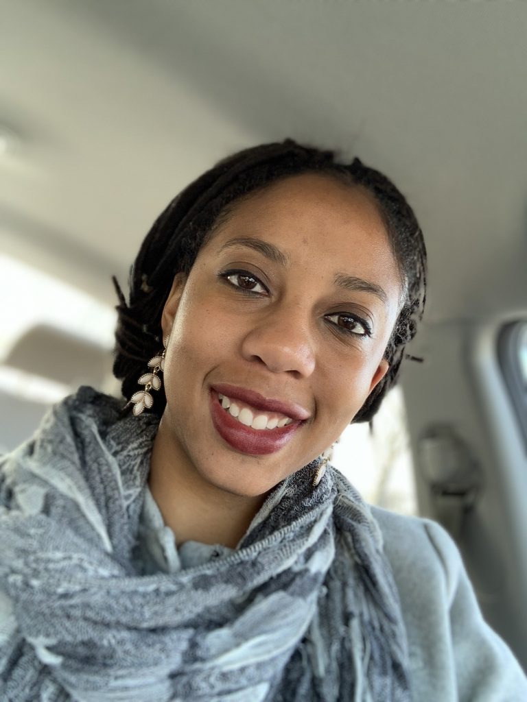 Pictured is Cassaundra Thorpe. Cassaundra is smiling and wearing a gray scarf.