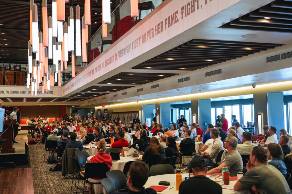 More than 200 coaches and leaders seated at round tables inside Camp Randall Stadium for the 2026 BIOS Leadership and Coaching Symposium.