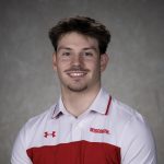 Charlie Matranga Headshot of Charlie Matranga, a smiling young man with dark hair, a mustache, and a goatee, wearing a white and red Wisconsin Under Armour polo shirt against a gray studio backdrop.